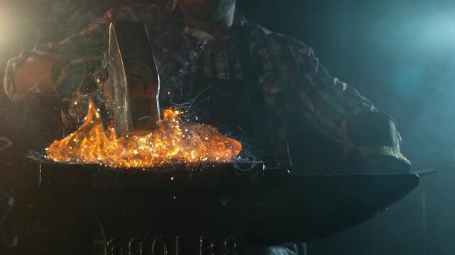 Close-up of blacksmith forging glowing hot iron on anvil with flying sparks. Super slow motion filmed on high-speed cinema camera at 1000 fps