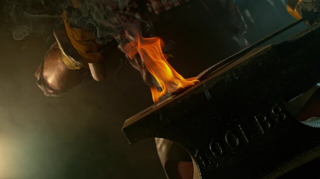 Close-up of blacksmith forging glowing hot iron on anvil with flying sparks. Super slow motion filmed on high-speed cinema camera at 1000 fps