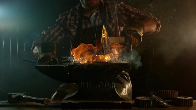 Close-up of blacksmith forging glowing hot iron on anvil with flying sparks. Super slow motion filmed on high-speed cinema camera at 1000 fps