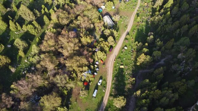Top down aerial view of a tourist campsite with tents and cars in a mountain forest, adventure base camp, Kazakhstan, Sayram-Ugam. High quality 4k footage