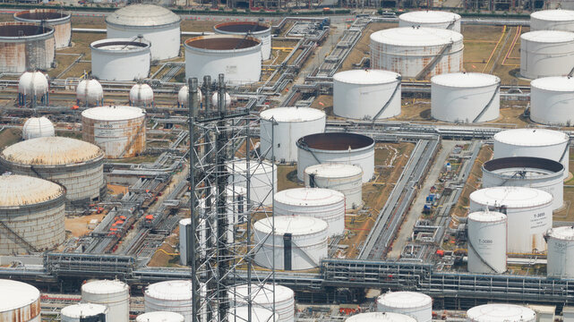 Aerial view of Bangchak Sriracha Refinery featuring large white oil storage tanks and a complex network of pipelines in Si Racha District, Chon Buri, Thailand.