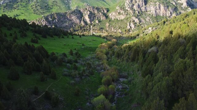 Aerial view of a lush green mountain valley with a winding stream and rocky cliffs, scenic nature landscape, Kazakhstan, Sayram-Ugam. High quality 4k footage