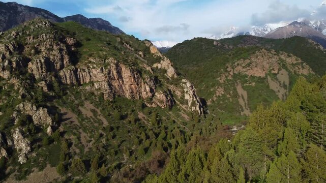 Aerial view of a mountain campsite in a green valley with snow-capped peaks in the background, adventure travel, Kazakhstan, Sayram-Ugam. High quality 4k footage