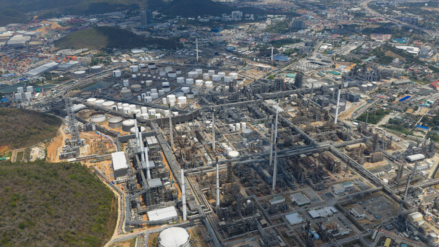 Aerial view of Bangchak Sriracha Refinery industrial complex with storage tanks, tall chimneys, and intricate piping systems Si Racha District, Chon Buri, Thailand.