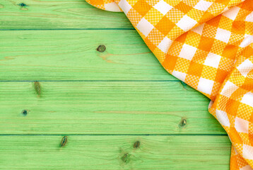 Fototapeta premium Checkered cloth on a green wooden table ready for a meal outside during a warm day in a garden setting