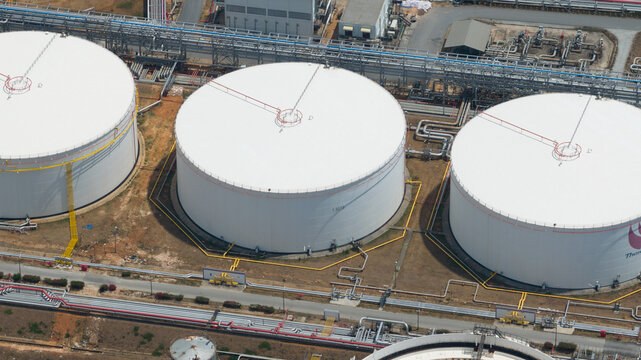 Aerial view of the Bangchak Sriracha Refinery featuring large white storage tanks and industrial piping systems in Si Racha District, Chon Buri, Thailand.