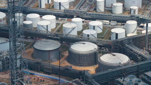 Aerial view of Bangchak Sriracha Refinery with large cylindrical storage tanks, complex pipeline networks, and industrial infrastructure in Si Racha District, Chon Buri, Thailand.