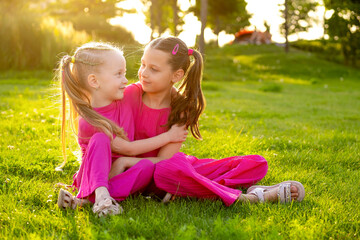 Fototapeta premium children in the park in summer, little girls walking and having fun on a green lawn, playing, summer holidays