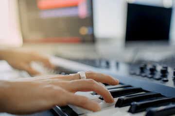 composer hands on piano keys in recording studio. music production technology, man is working on pianino and computer keyboard on desk. close up concept. © Vlad