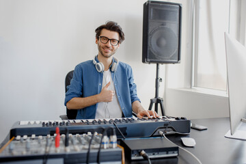 Thumb up. Composer hands on piano keys in recording studio. music production technology, man is working on pianino and computer keyboard on desk. Good specialist. Confidence and Professionalism © Vlad