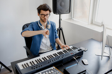 thumbs down. Composer hands on piano keys in recording studio. music production technology, man is working on pianino and computer keyboard. Bad employee and specialist. Frustrated and Unprofessional. © Vlad
