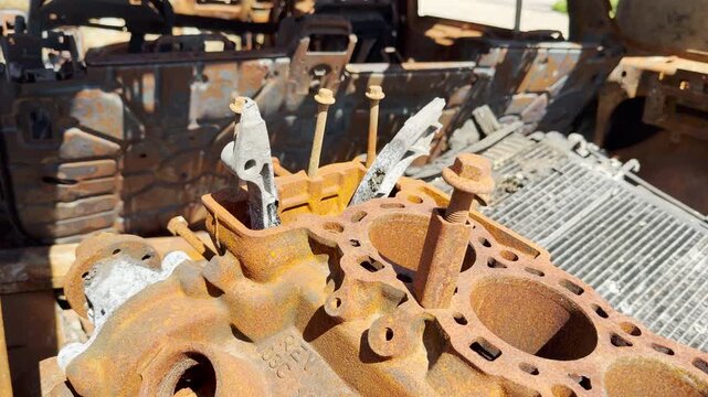 A close-up view reveals a heavily rusted engine block sitting inside a destroyed vehicle. The corroded metal and scorched frame evoke a sad, dramatic feeling of total abandonment.