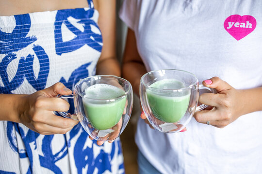 Two women holding cups of matcha green tea, showcasing a moment of relaxation