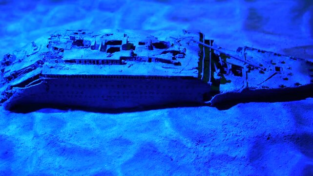 Miniature scale model of the rms titanic shipwreck resting on the sandy ocean floor after sinking in the deep, cold blue waters of the atlantic ocean, a famous historical maritime disaster