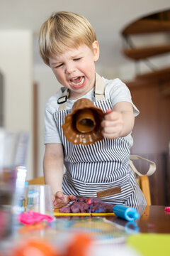 Blond boy sculpts from plasticine at home at the table. The idea and concept of the school, home education and developmental activities.