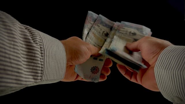 Hands counting Saudi Arabian Riyal banknotes on black background