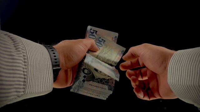 Hands counting Saudi Arabian Riyal banknotes on black background