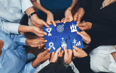 Diverse corporate officer workers collaborate in office, connecting puzzle pieces to represent partnership and teamwork. Unity and synergy in business concept by merging jigsaw puzzle. Concord Amity © InfiniteFlow