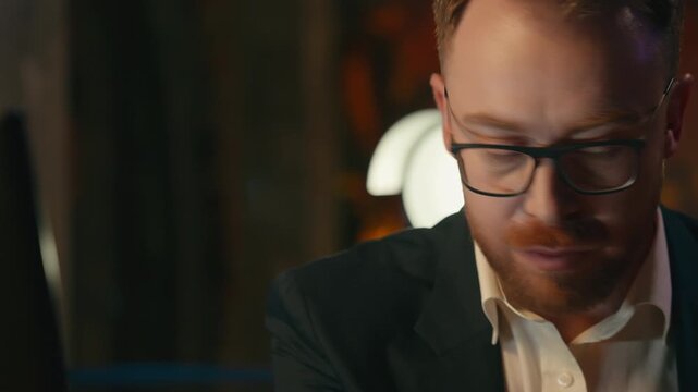 Caucasian business man businessman in evening office reading notes typing computer guy male agent looking in notebook stats data checking working with pc manager at desk night research corporate work