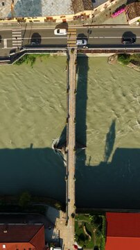 Vertical Aerial Top Down Establishing Traffic Crossing Stone Bridge Over River in Fort Bard Italy