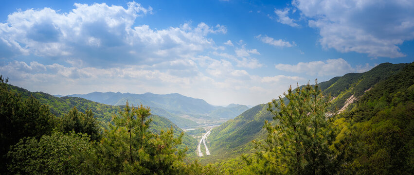 Panoramic landscape of Ihwaryeong Pass with modern highway through mountain valley, South Korea (High angle vista of road infrastructure and layered mountain ranges under cloudy sky)