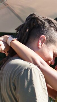Vertical video: Raising arms woman in yellow wrapping partner at patio showing care with pale watch