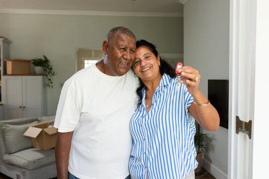Senior African American couple at doorway holding keys with red fob, man tee, woman striped shirt