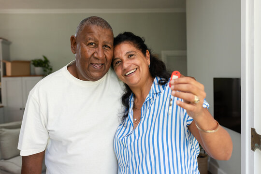 African American senior couple standing in doorway at home holding red key fob and jewelry