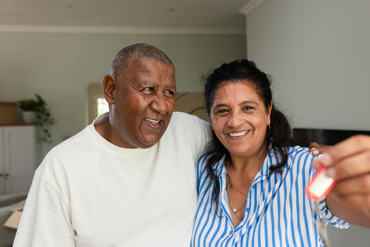 Senior African American couple standing at home smiling, woman holding house key on red keychain
