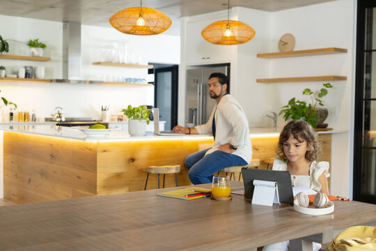 African American dad sitting on island, watching youth daughter using tablet headset, copy space