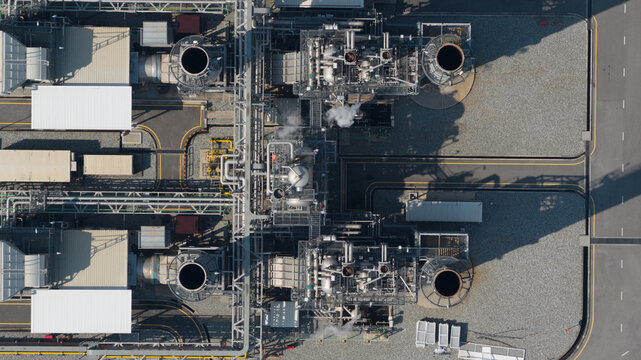 Aerial view of Amata B.Grimm Power Rayong 5 power plant with industrial machinery, chimneys, and complex piping systems in Map Yang Phon, Rayong, Thailand.