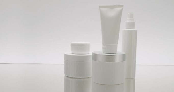 White Bottle and tubes for cosmetics on a white background in studio, truck right. Cosmetics oils based on natural ingredients, scrub, tonic, body care. Glossy cosmetic jar with cream.