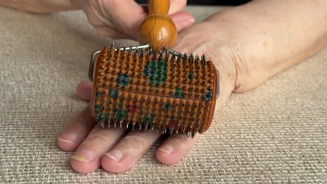 Elderly hand receiving needle roller close-up showing wrinkled skin, magnetic spiked roller gliding across back of hand, gentle