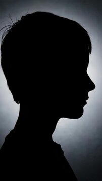 High-contrast silhouette portrait of a child's side profile against a softly lit gray background, highlighting clean facial contours, short hair outline, and dramatic rim lighting.
