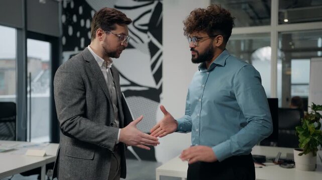Two multiracial business men talking looking in folder with papers handshaking leaving office diverse businessmen Caucasian leader reading report contract shaking hands with Arabian manager going away
