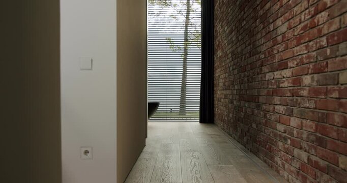A sleek and stylish corridor in a modern home featuring a red brick wall, wooden flooring, and natural light filtering through blinds. Modern Home Interior with Brick Wall and Wood Flooring