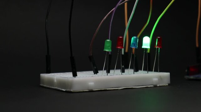 Electronic prototyping projects on a breadboard with multiple colored LED glowing one by one. Breadboard with simple LED circuit