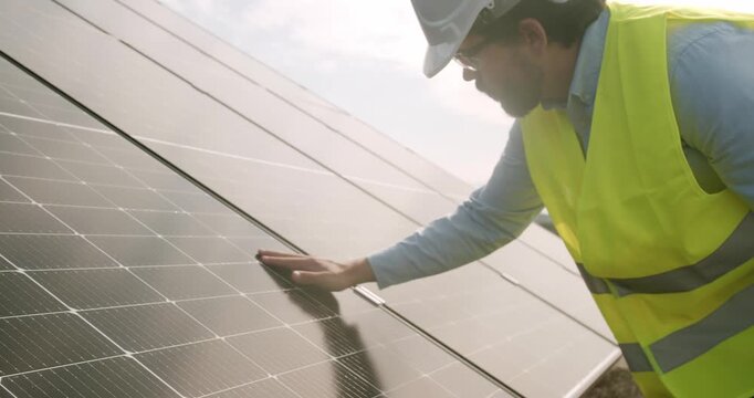 Crop man touching solar panel. Male engineer in shirt touching surface of photovoltaic panel at sunset. Technician connecting solar panel.