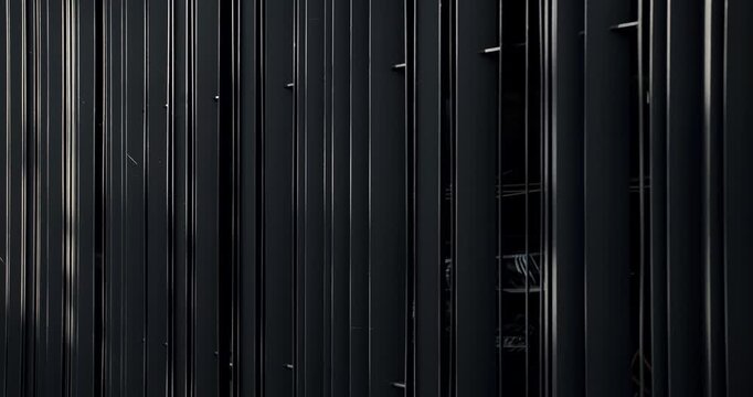 Dark abstract background featuring a pattern of vertical black lines with a metal texture. Suitable for concepts related to modern design, minimalism, and art.