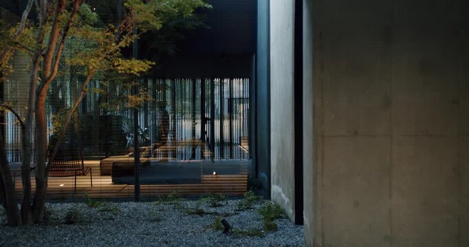 A serene evening scene showing a modern home interior, visible through slatted blinds and trees, highlighting contemporary architecture and peaceful residential design. Elegant Design