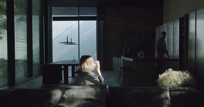 A serene modern home scene, featuring a couple relaxed by the natural light streaming in from a large window. The setting conveys a sense of stylish domestic life. Modern Home Interior