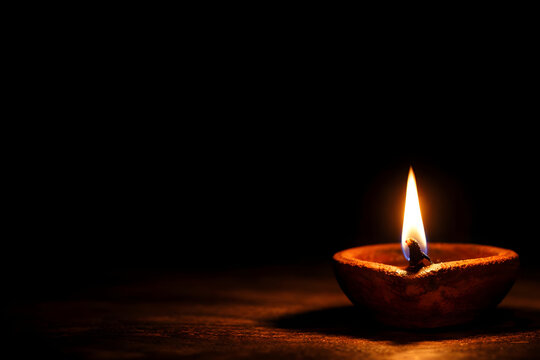 Lit Clay Oil Lamp with Flame on Dark Background