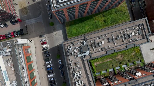 Top down aerial view of a modern office building with green roof, industrial HVAC system and parking lot in the city business district.