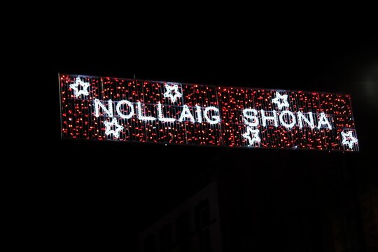 Night time outdoor Christmas light display reading Nollaig Shona, Happy Christmas in Irish (Gaeilge), copy space