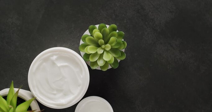 Cosmetics oils based on natural ingredients, scrub, tonic, body care. Jars, bottles and tubes with green eco leafs for cosmetics and Beauty treatment spin on a black background. Top View.