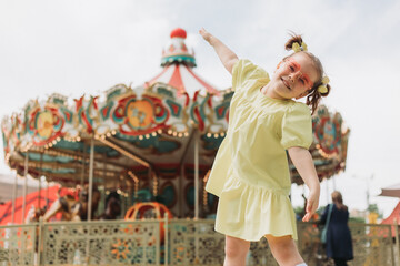 happy little girl in front of a carousel at an amusement park in the summer © Tina kids photo