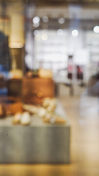 Vertical blurred background of a modern retail interior with warm lighting and display counters