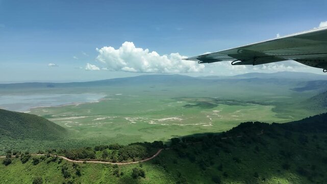 aerial flight along the green ngorongoro crater after the rains with aircraft wing in view