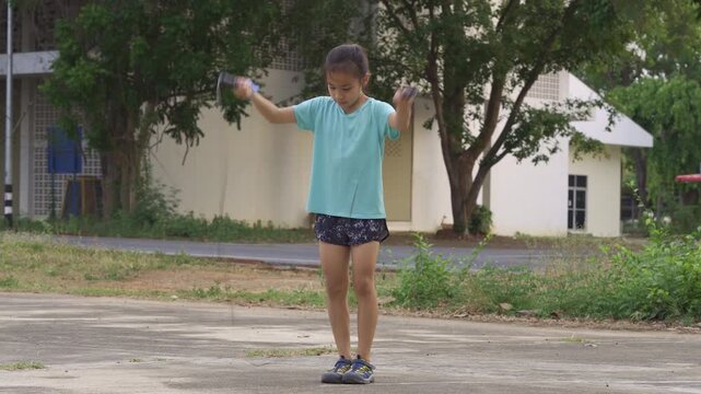 Back to school physical education: Asian girl jumping rope outdoors for exercise and fitness.