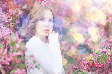 Naklejka premium Springtime background, a woman in pink in a blooming cherry orchard, a model posing in a romantic style